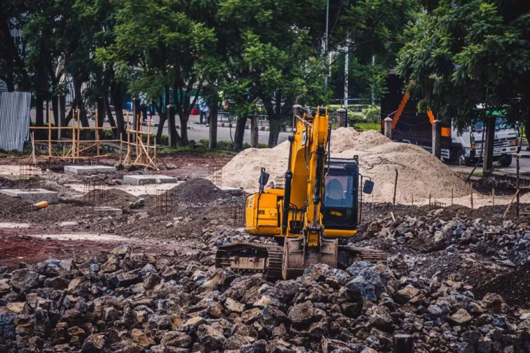 Excavator working loose soil on a site during land clearing and excavation