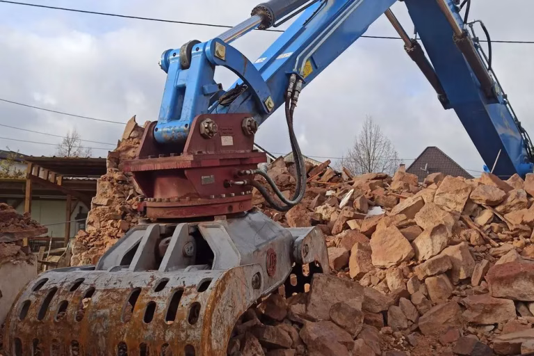 Excavator breaking out concrete rubble during slab and foundation removal